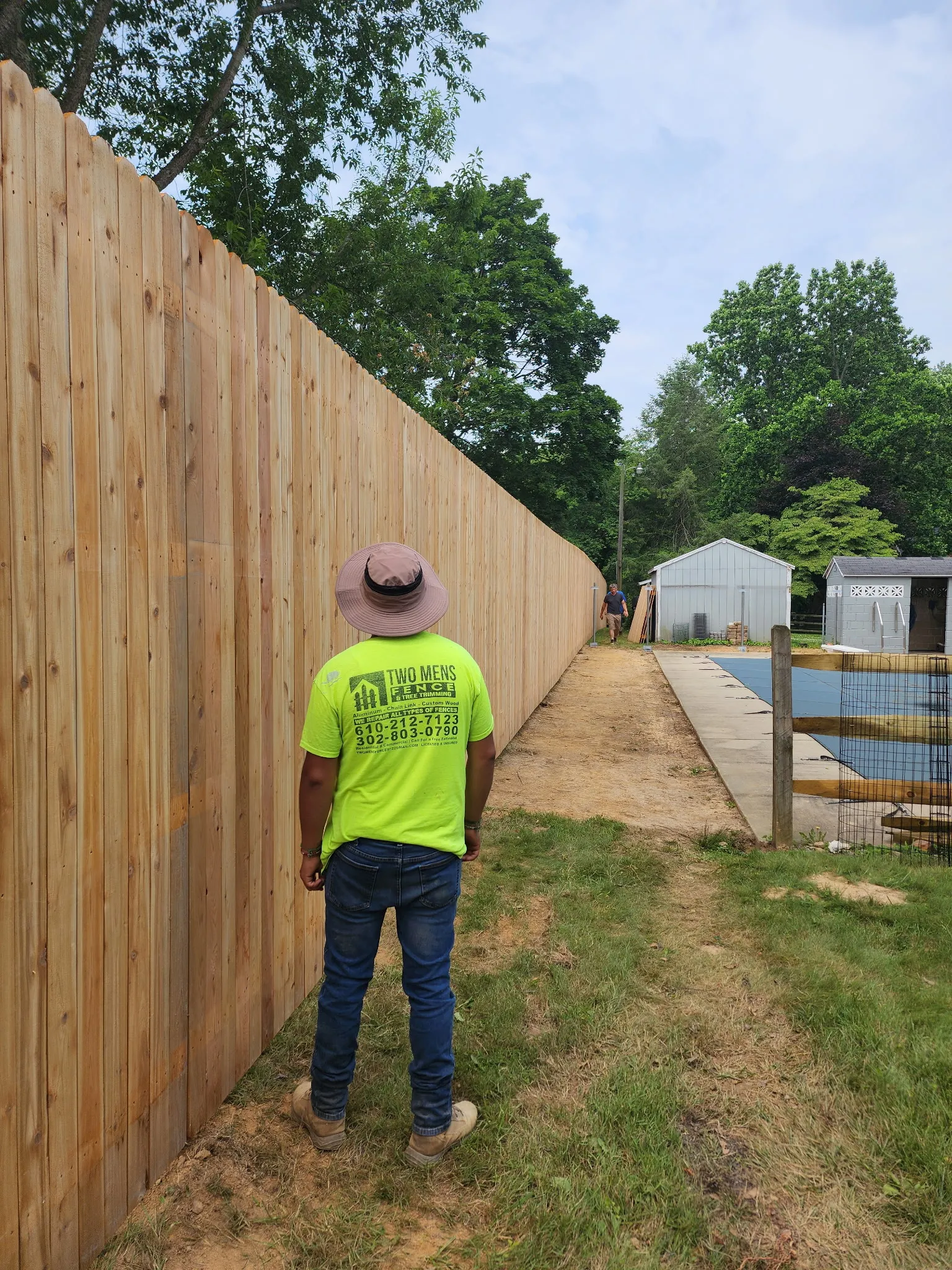 TWO MEN crew member inspecting tall cedar privacy fence installation in Delaware